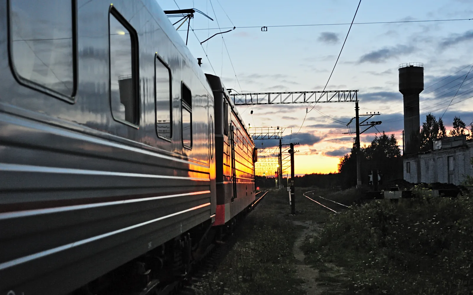 A blue and white passenger train positioned at Kem station with station buildings visible in the background